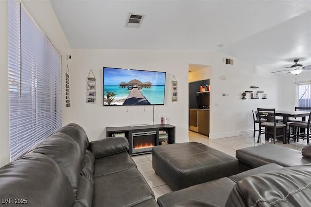 tiled living room with a fireplace, vaulted ceiling, and ceiling fan