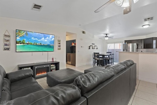 living room with ceiling fan, a fireplace, light tile patterned floors, washing machine and dryer, and vaulted ceiling