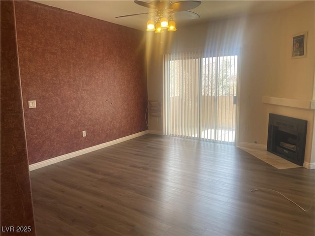 unfurnished living room featuring ceiling fan, dark hardwood / wood-style floors, and a tiled fireplace