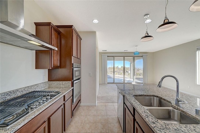 kitchen featuring pendant lighting, sink, light stone counters, stainless steel appliances, and wall chimney range hood