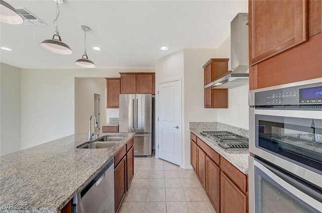 kitchen featuring sink, light tile patterned floors, hanging light fixtures, stainless steel appliances, and wall chimney exhaust hood