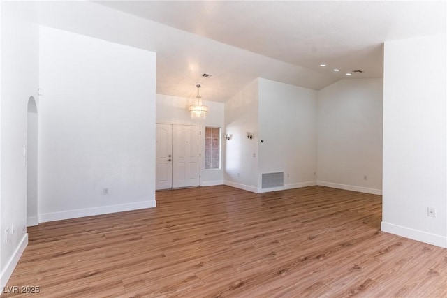 empty room with light wood-type flooring and vaulted ceiling