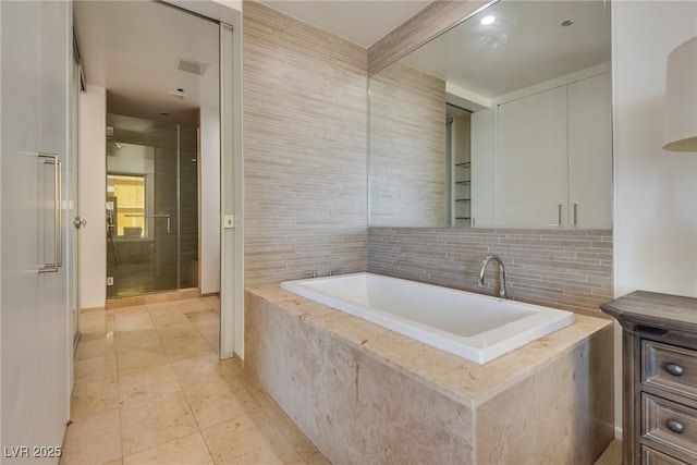 bathroom with tile patterned flooring and tiled tub