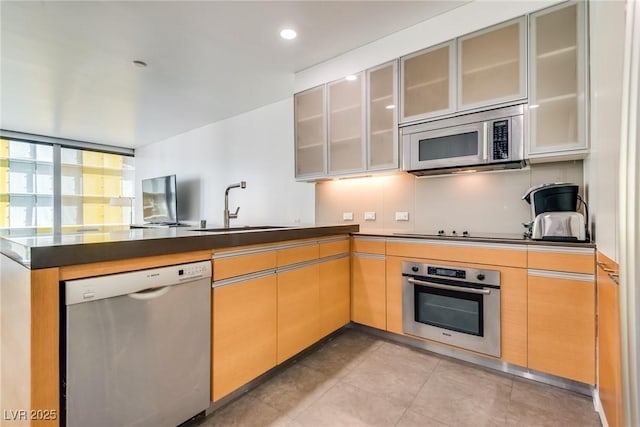 kitchen with light brown cabinetry, sink, appliances with stainless steel finishes, and kitchen peninsula