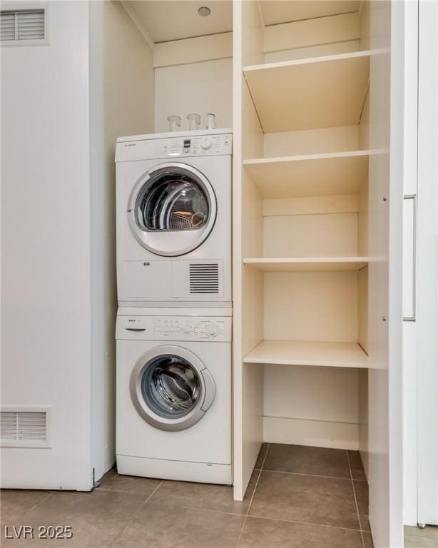 laundry room featuring stacked washer / dryer and tile patterned flooring