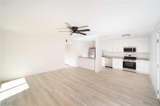 kitchen featuring appliances with stainless steel finishes, white cabinetry, sink, light hardwood / wood-style flooring, and ceiling fan