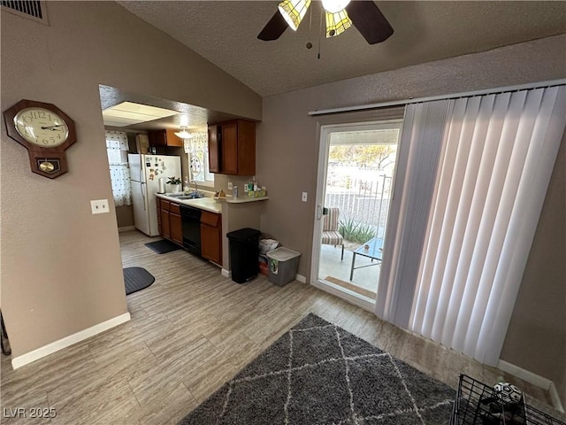 kitchen featuring a textured ceiling, dishwasher, lofted ceiling, and white refrigerator