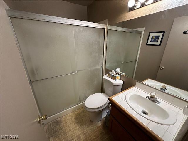 bathroom featuring vanity, toilet, and a shower with door