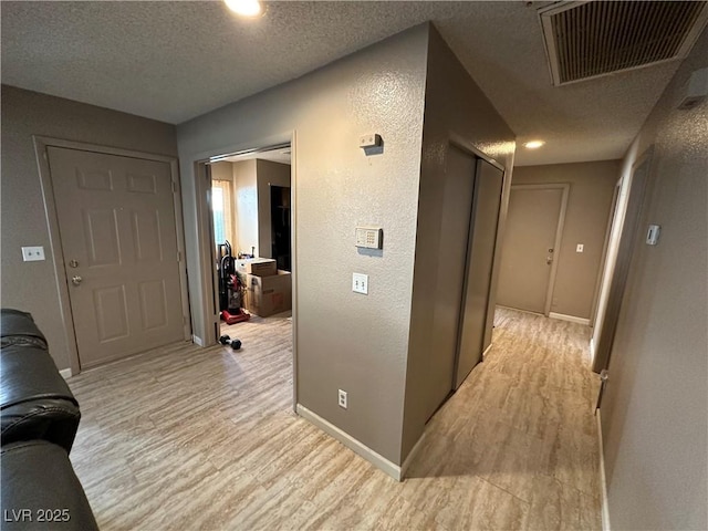 hall featuring light hardwood / wood-style flooring and a textured ceiling