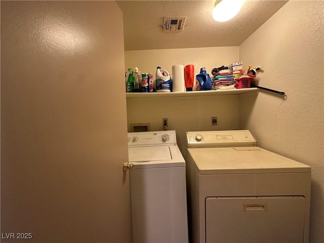 clothes washing area with washer and dryer and a textured ceiling