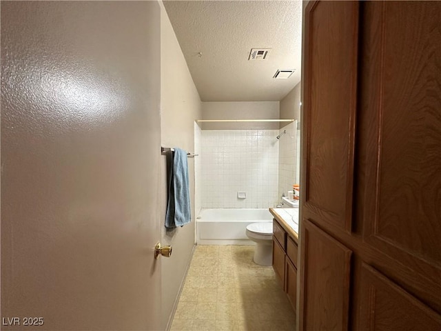 full bathroom featuring a textured ceiling, toilet, vanity, and tiled shower / bath combo