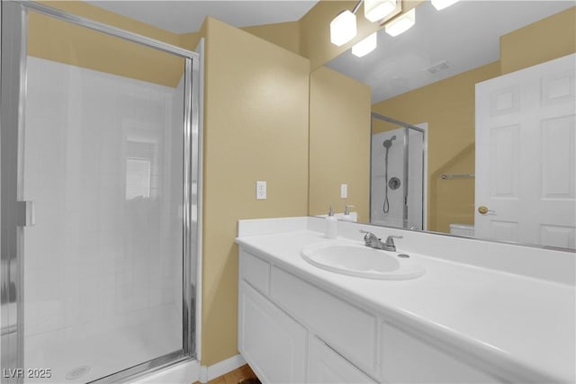 bathroom featuring toilet, vanity, and a shower with shower door