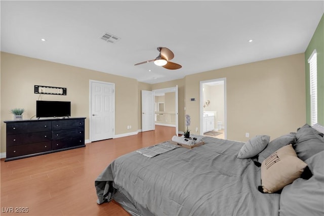 bedroom featuring wood-type flooring, ceiling fan, and ensuite bath