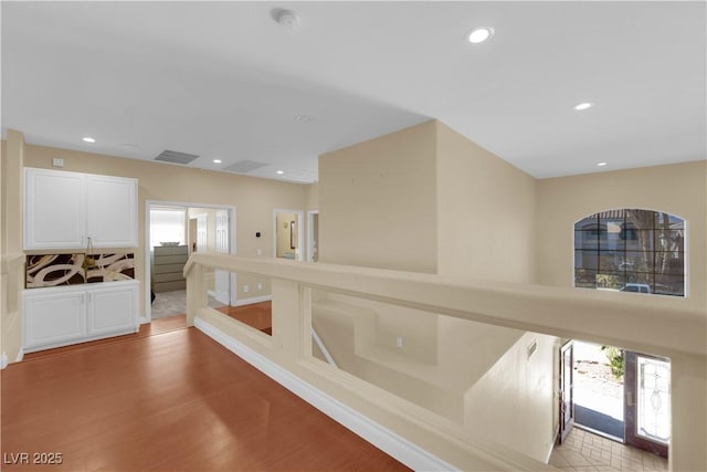 hallway with a wealth of natural light, light hardwood / wood-style flooring, and french doors