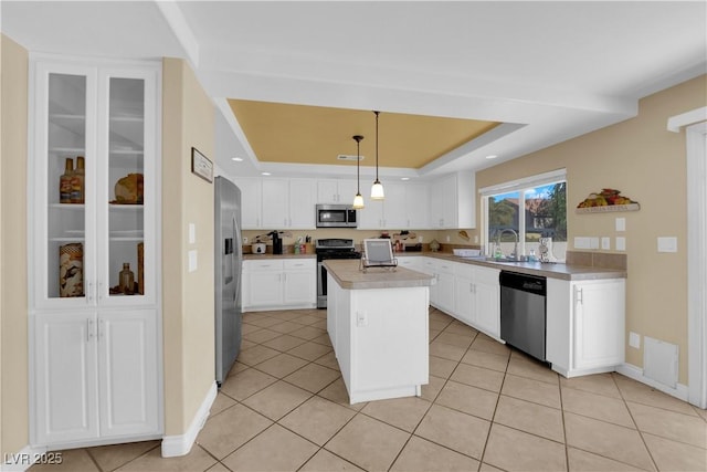 kitchen with decorative light fixtures, white cabinetry, a center island, a tray ceiling, and stainless steel appliances