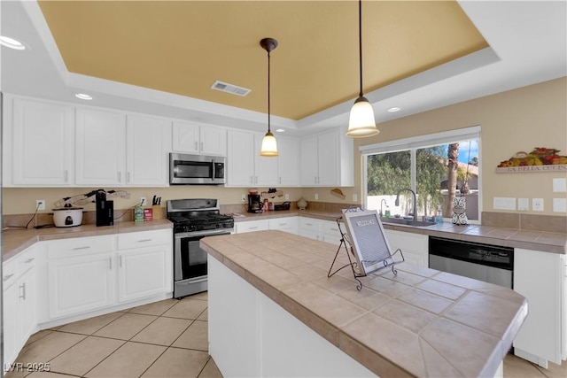 kitchen featuring stainless steel appliances, sink, pendant lighting, and a tray ceiling