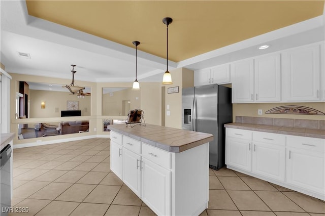 kitchen with pendant lighting, appliances with stainless steel finishes, white cabinetry, light tile patterned flooring, and a raised ceiling