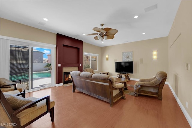 living room with ceiling fan, a fireplace, and light hardwood / wood-style flooring