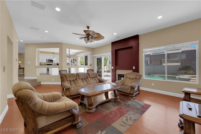 living room featuring hardwood / wood-style flooring, a large fireplace, and ceiling fan