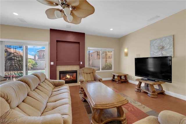 living room with a fireplace, wood-type flooring, and ceiling fan