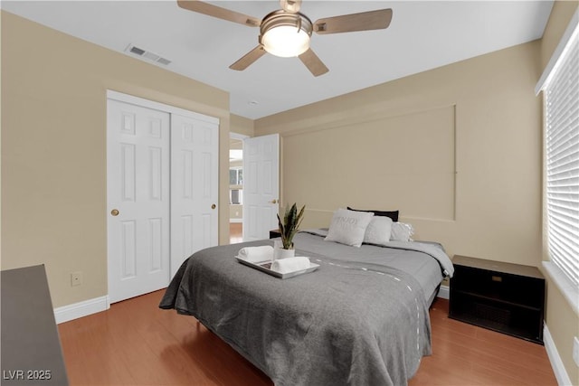 bedroom with ceiling fan, wood-type flooring, and a closet