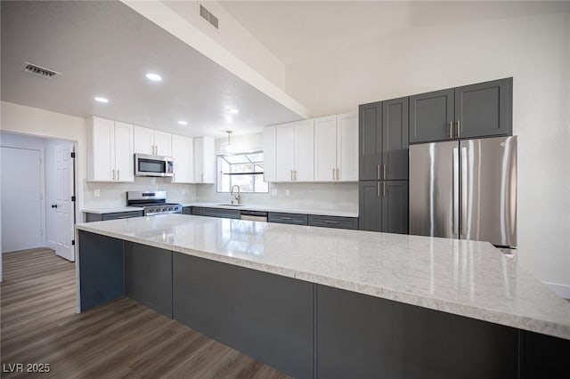 kitchen featuring sink, stainless steel appliances, white cabinetry, and light stone counters