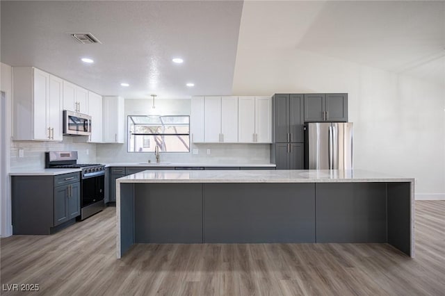 kitchen featuring white cabinets, light hardwood / wood-style floors, appliances with stainless steel finishes, and sink