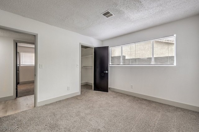 unfurnished bedroom featuring light colored carpet, a textured ceiling, and a closet