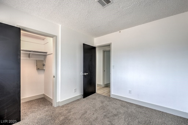 unfurnished bedroom with a textured ceiling, light colored carpet, and a closet