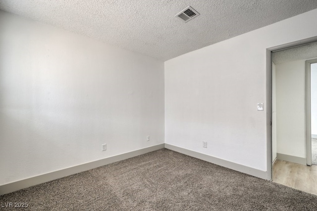 carpeted empty room with a textured ceiling