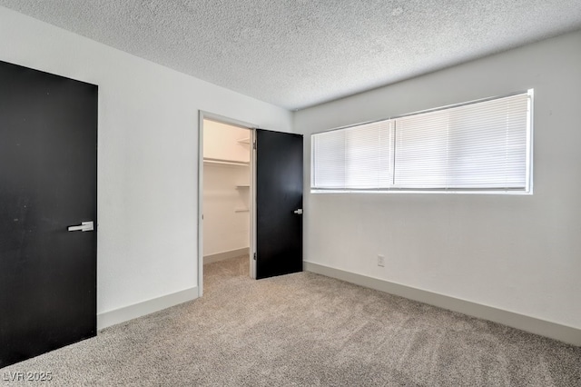 unfurnished bedroom featuring a closet, light colored carpet, a spacious closet, and a textured ceiling