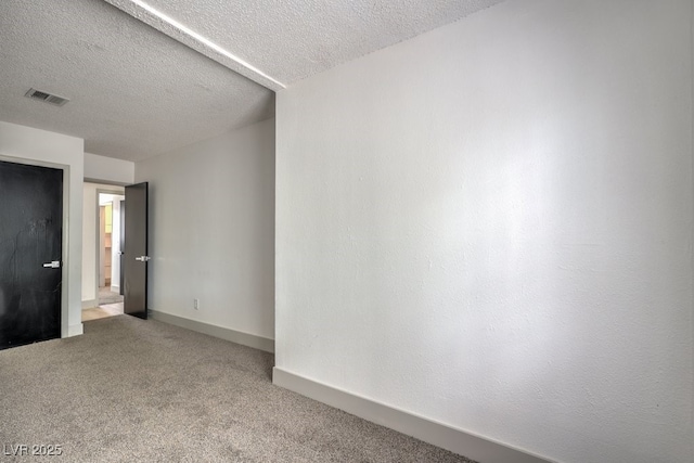 carpeted empty room featuring a textured ceiling