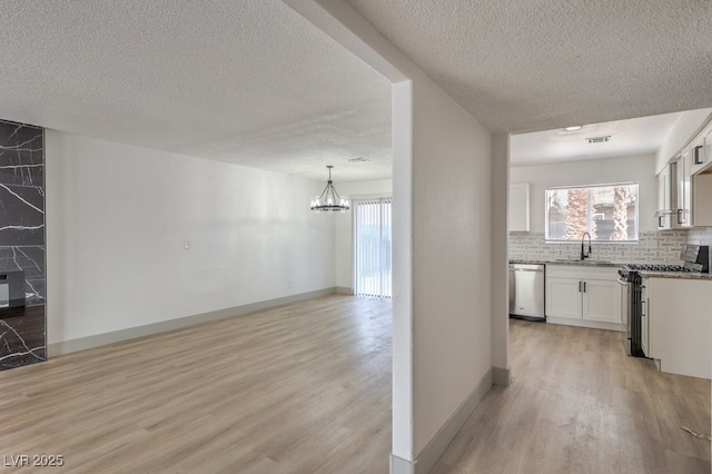 kitchen with sink, backsplash, white cabinetry, a healthy amount of sunlight, and stainless steel appliances