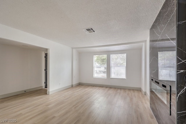 unfurnished living room featuring light hardwood / wood-style floors and a textured ceiling