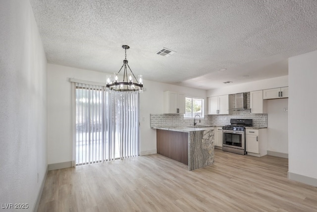 kitchen with wall chimney exhaust hood, white cabinetry, sink, kitchen peninsula, and stainless steel range with gas stovetop