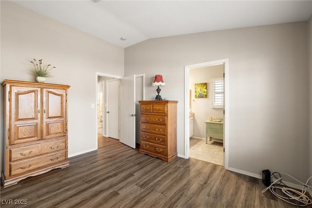 bedroom featuring connected bathroom, vaulted ceiling, and dark hardwood / wood-style flooring