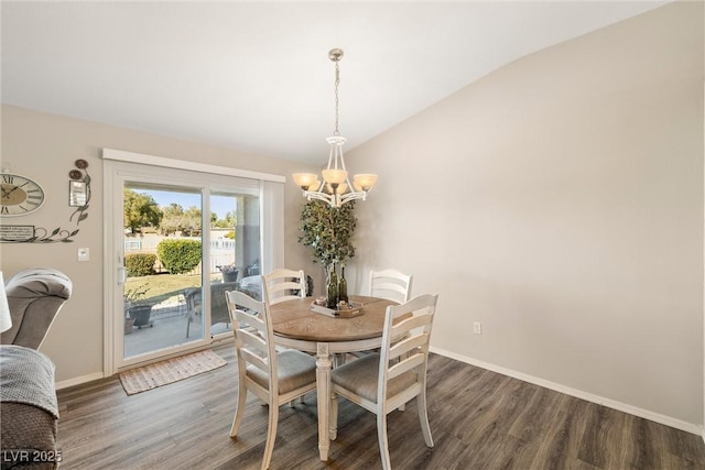 dining room featuring dark wood-type flooring, an inviting chandelier, and vaulted ceiling