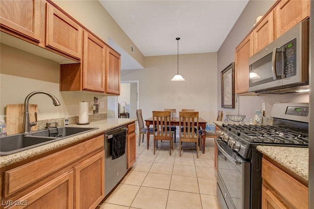 kitchen featuring pendant lighting, sink, light stone counters, light tile patterned flooring, and stainless steel appliances