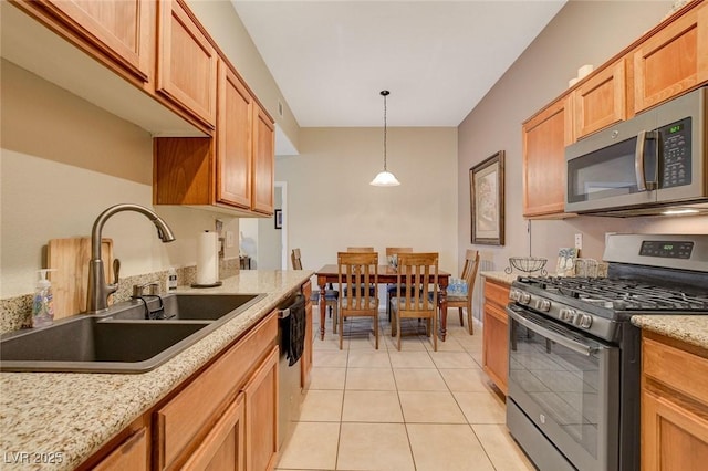 kitchen with pendant lighting, sink, light tile patterned floors, light stone counters, and stainless steel appliances