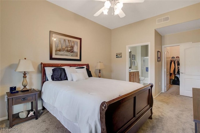 bedroom featuring ceiling fan, light colored carpet, ensuite bath, a spacious closet, and a closet