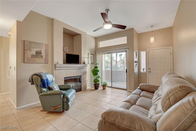 tiled living room with a tiled fireplace and ceiling fan