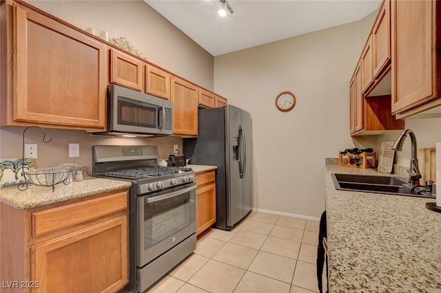 kitchen featuring sink, light tile patterned floors, light stone countertops, and stainless steel appliances