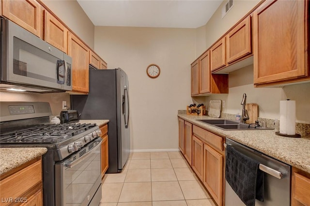 kitchen featuring light stone counters, sink, light tile patterned floors, and stainless steel appliances