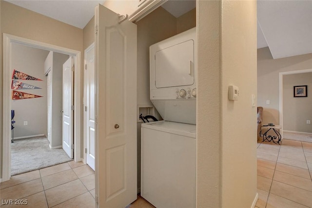 laundry area with light tile patterned floors and stacked washer and clothes dryer