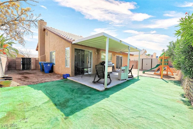 back of property featuring a patio, a playground, a yard, and a storage unit