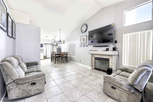 living room with light tile patterned floors, baseboards, high vaulted ceiling, a fireplace, and a notable chandelier