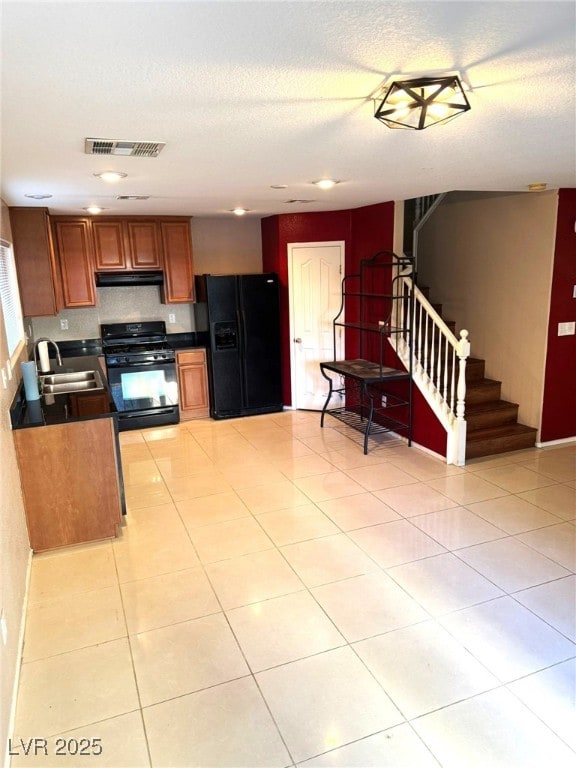 kitchen featuring sink, light tile patterned flooring, black appliances, and a textured ceiling