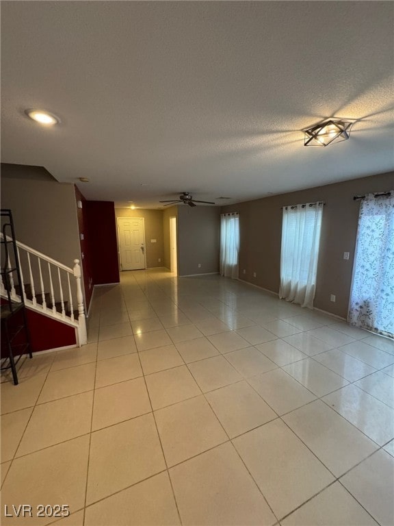 empty room featuring light tile patterned flooring, a textured ceiling, and ceiling fan