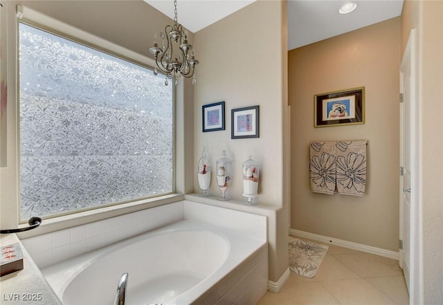 bathroom featuring an inviting chandelier, a relaxing tiled tub, and tile patterned flooring