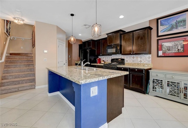 kitchen with black appliances, decorative backsplash, dark brown cabinets, light stone counters, and a center island with sink